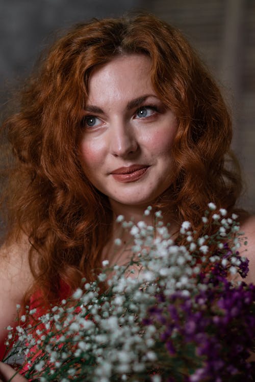 A Beautiful Woman Smiling while Holding Flowers