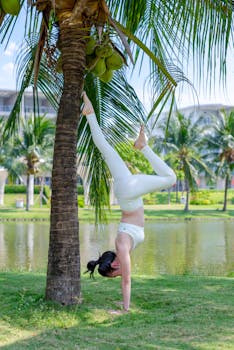 A woman doing a yoga handstand against a palm tree in a park in Ho Chi Minh City.