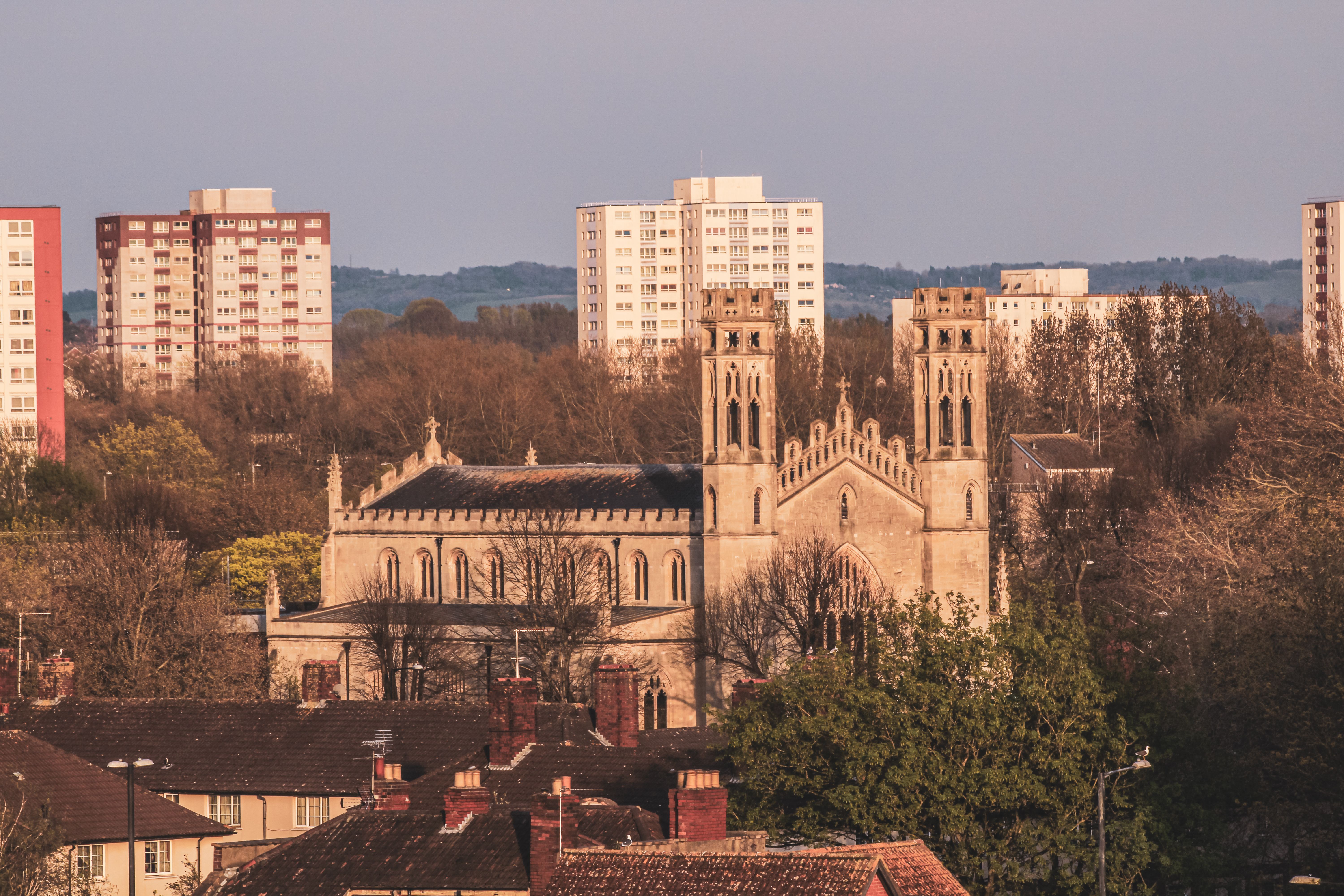 A historic church stands amid modern high-rise buildings at sunset.