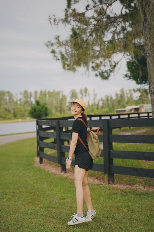 Free Woman in Brown T-shirt and Black Shorts Standing on Green Grass Field Stock Photo