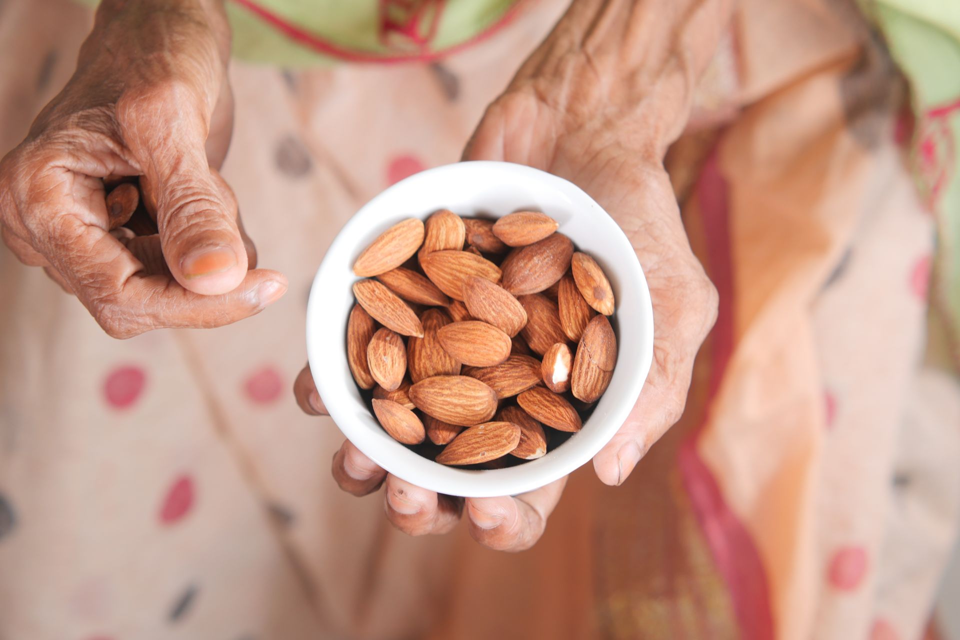 Overhead Shot of a Person Holding a Bowl with Almond Nuts