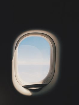 View through an airplane window showing a peaceful and clear sky.