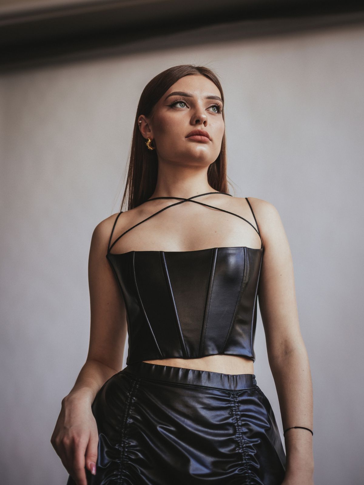 Editorial fashion image showing a black leather corset styled with a matching skirt