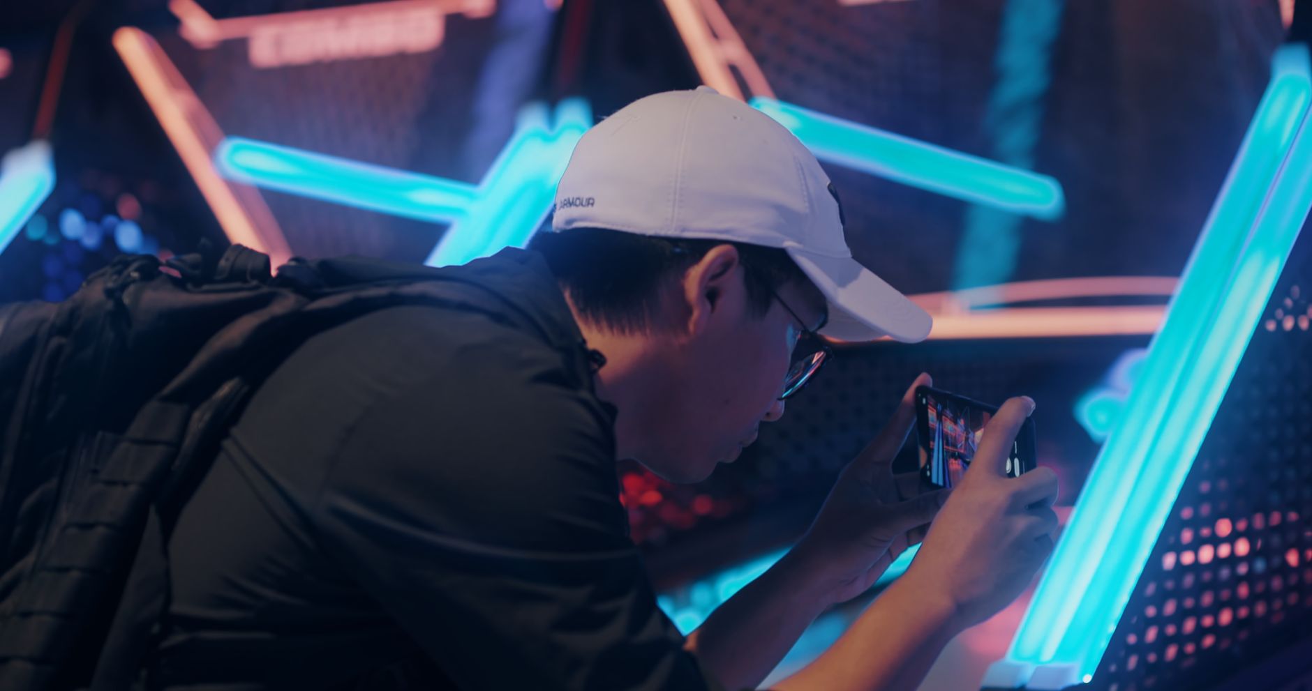 A man taking a picture of neon lights using a smartphone in a stylish urban setting.