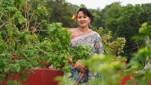 Woman in a Sari Dress Smiling Near Plants