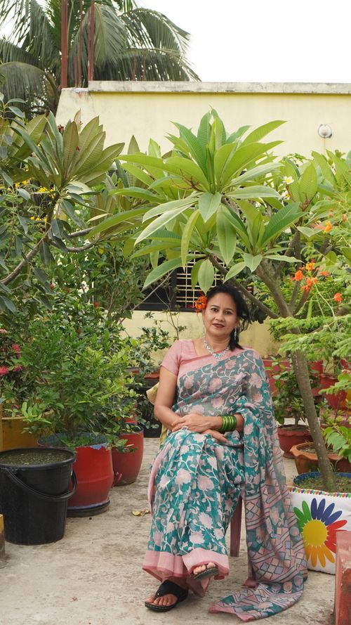 Free A woman in a traditional saree sitting in a garden surrounded by lush greenery. Stock Photo