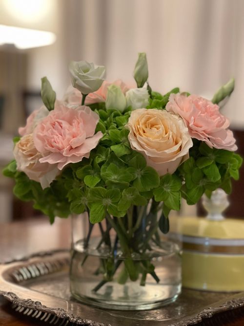 Free A beautiful arrangement of pink roses and green foliage in a glass vase, creating an elegant indoor decoration. Stock Photo