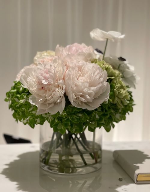 Free A beautiful arrangement of peonies and hydrangeas in a clear vase, perfect for decor inspiration. Stock Photo