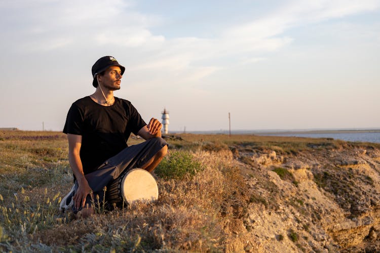 Man With A Bucket Hat Kneeling Near A Drum