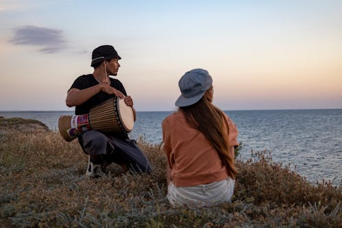 A Man Playing a Drum Near a Woman