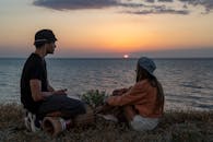 Man with a Drum Sitting Near the Sea During Sunset