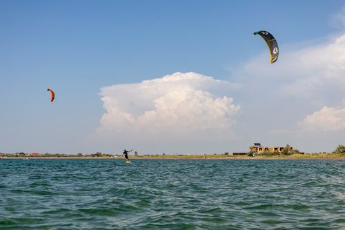 Free Dynamic kiteboarding scene on a serene lake during a bright summer day, perfect for recreation and leisure. Stock Photo