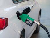 Gas pump nozzle in the fuel tank of a white car, refuel
