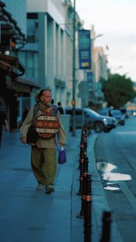 A man carrying a colorful bag walks on a street in Konya, Turkey. Urban scene.