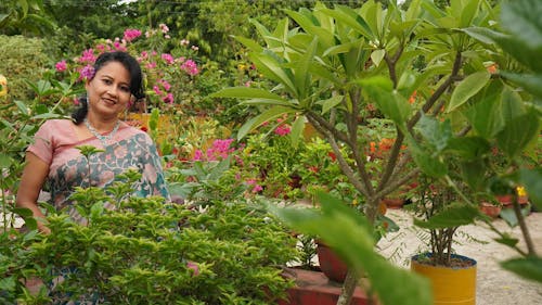 A Smiling Woman Near the Green Plants