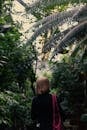 Woman in Black Long Sleeve Shirt Standing Near Green Palm Tree