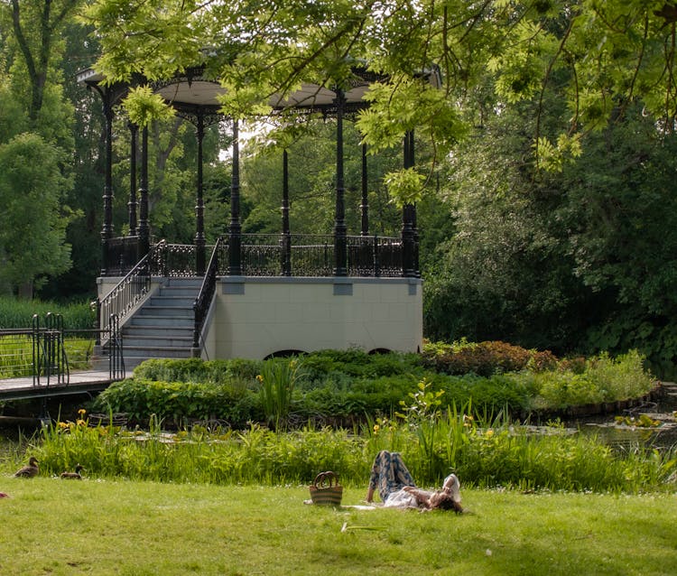 Woman Lying On Grass Near A Gazebo 