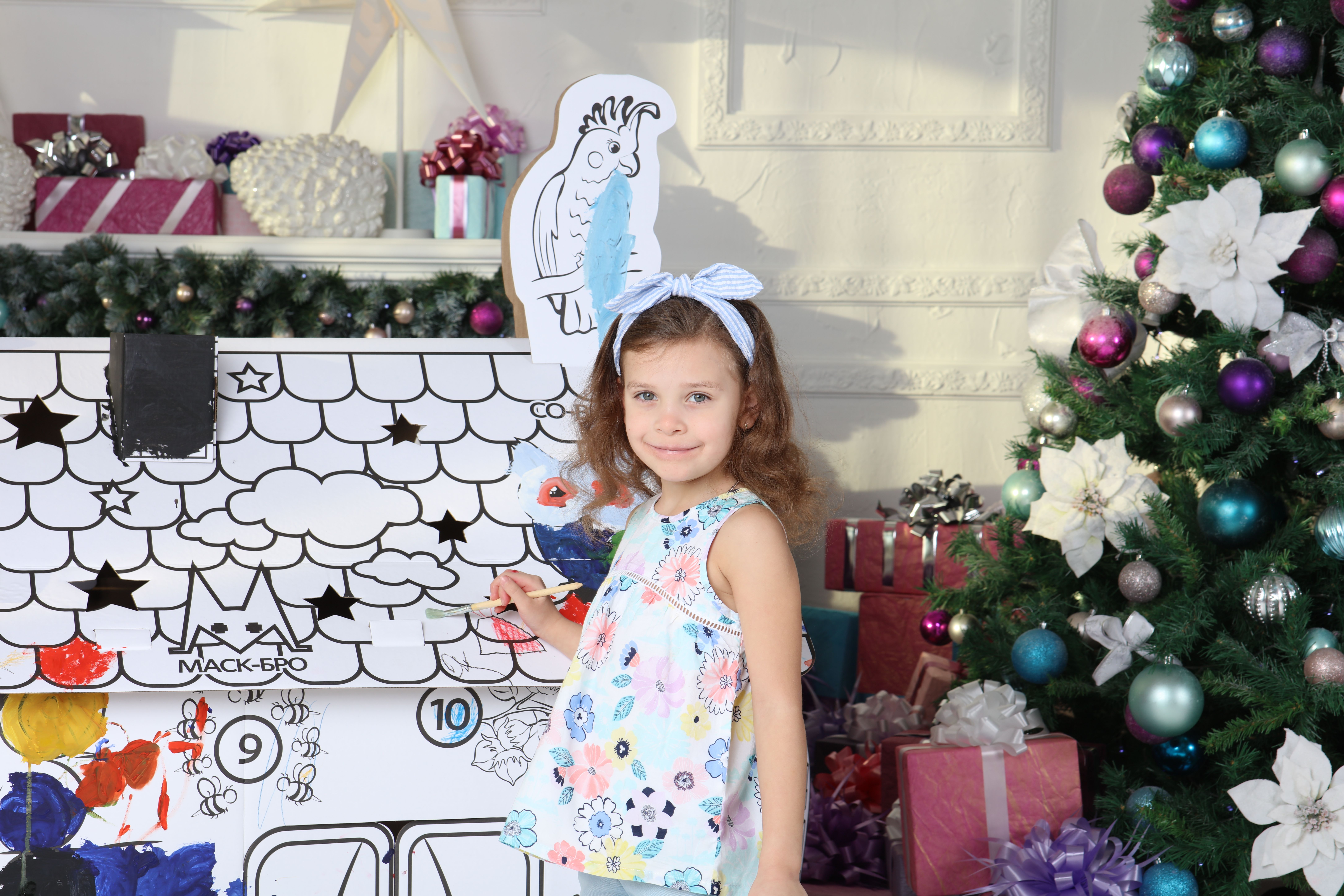 Young girl with floral blouse painting an Advent calendar in a festive room with gifts and Christmas tree. - Photo by MASKBRO on Pexels