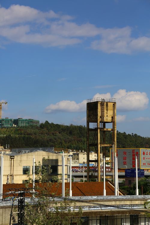Free A towering structure amidst an industrial setting with a hill and blue sky backdrop. Stock Photo