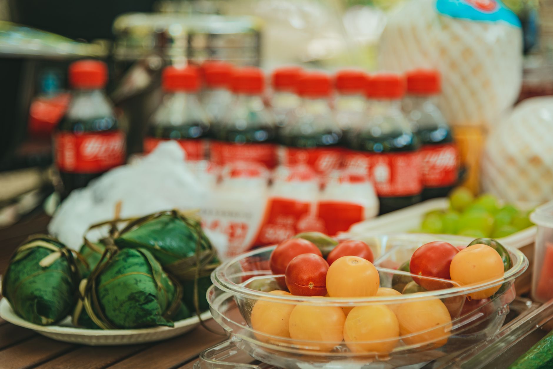 Vibrant display of Coca-Cola bottles and fresh tomatoes in an outdoor market setting.