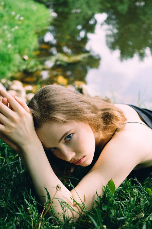Portrait of a Woman Lying in Grass next to a Pond