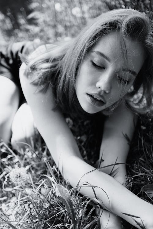 Free Grayscale Photo of Woman Lying on Grass Stock Photo