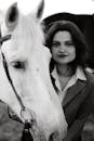 Grayscale Photo of Woman in Button Up Shirt Beside Horse