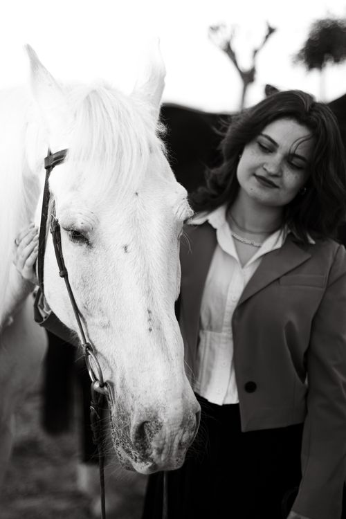 Free Grayscale portrait of a woman standing with a white horse, exuding companionship and elegance. Stock Photo