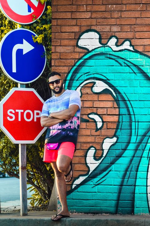 Free Man posing near vibrant street art and road signs on a sunny day. Stock Photo