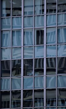 Close-up of a modern building facade with reflective glass windows creating abstract patterns.