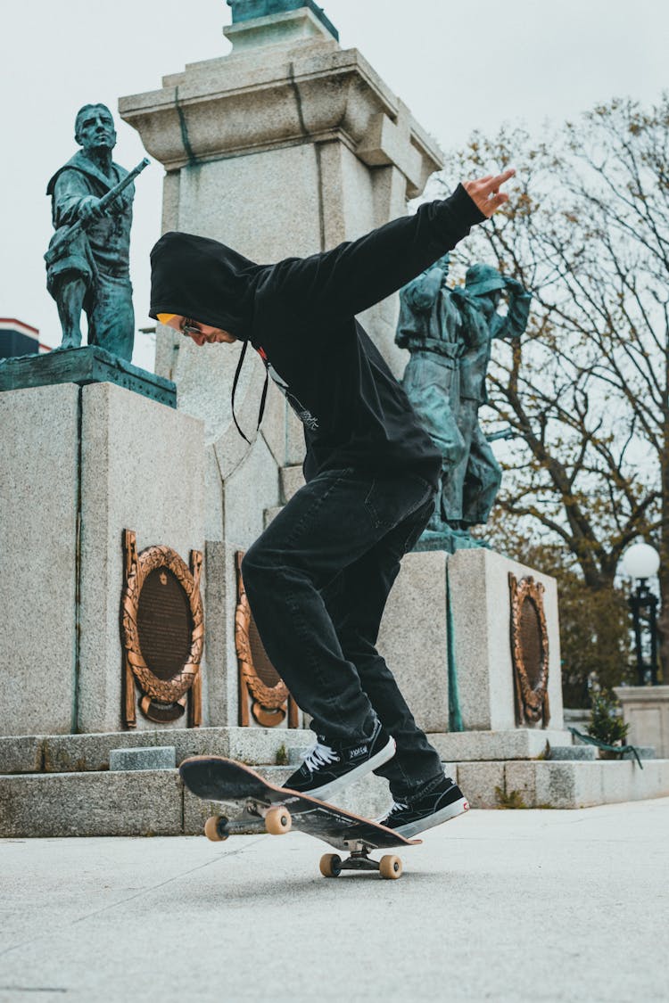 A Man In Black Jacket And Black Pants Skating In The Park