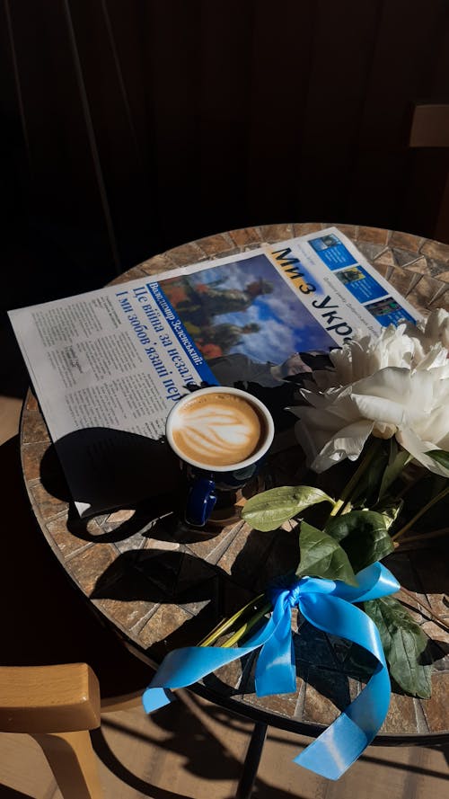 Free Cup of Coffee Beside a Newspaper and White Flowers Stock Photo