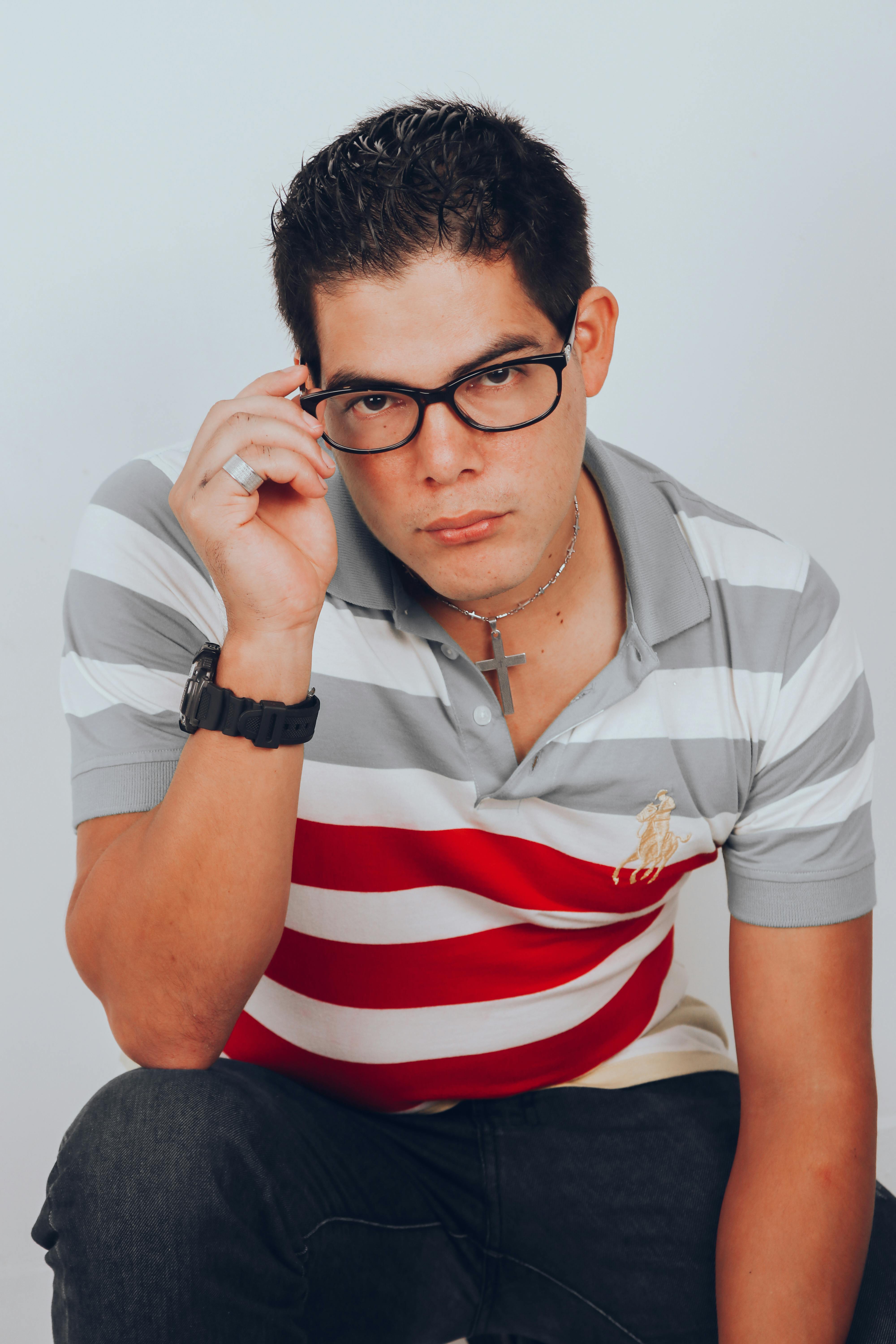 Portrait of a confident man wearing eyeglasses and a striped polo shirt indoors.