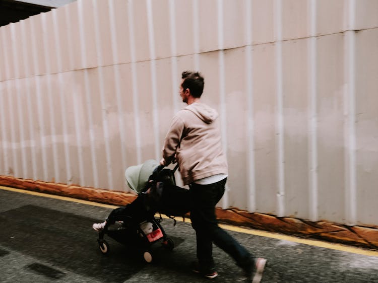 Man In Hoodie Sweater Pushing A Stroller