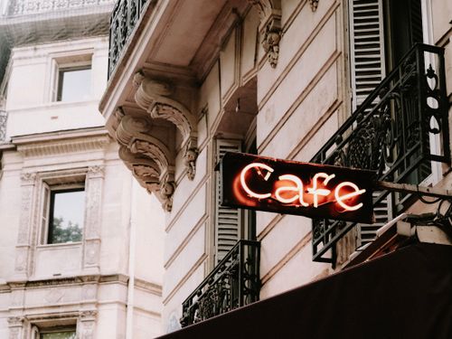 Free Charming European architecture featuring a Parisian cafe sign and ornate balcony. Stock Photo