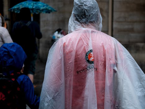 People walking in rain with umbrellas and raincoats, creating a moody city scene.
