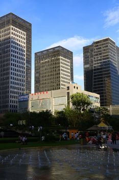 View of urban park with modern skyscrapers and people enjoying the space.