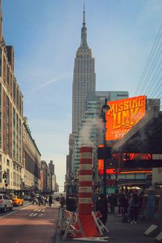 Empire State Building view with lively NYC street scene, steam vent, and signage.
