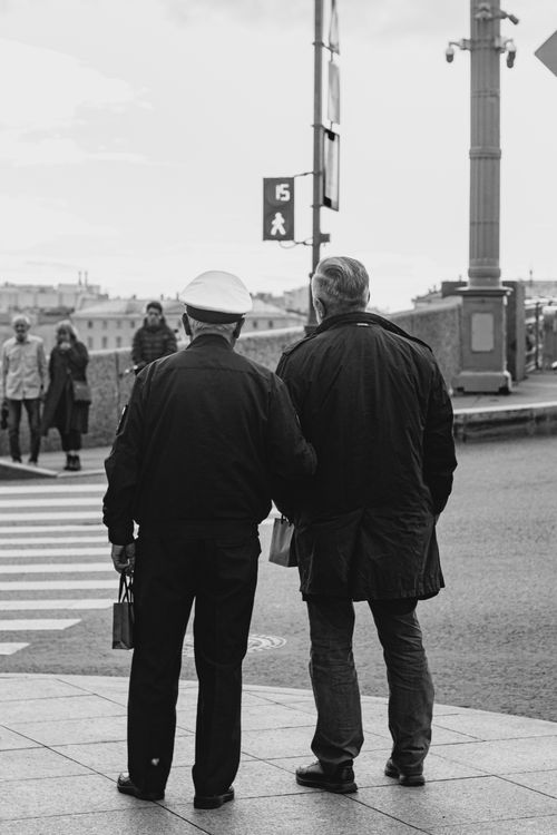 Free Black and white photo of two men standing at a zebra crossing in an urban setting. Stock Photo