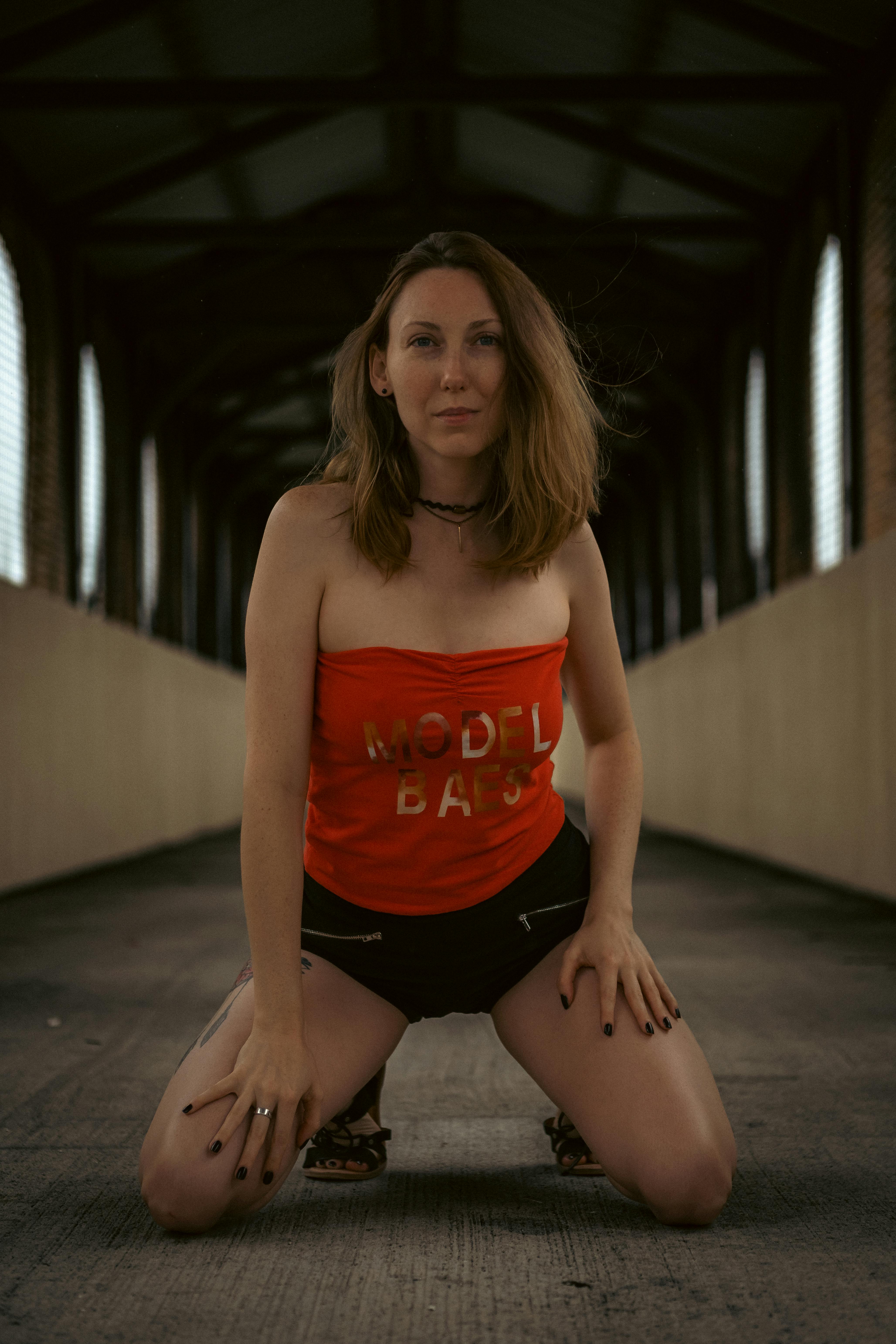 Stylish woman in a red top and shorts posing confidently on a bridge.