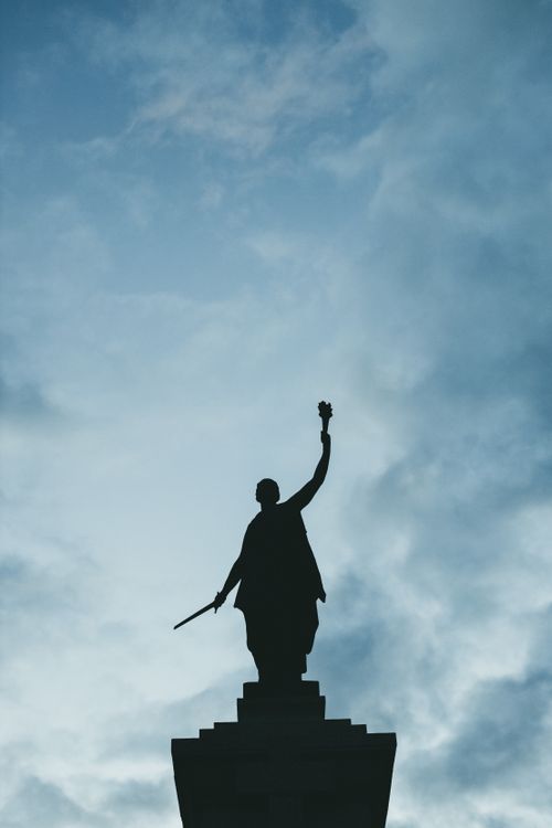 Free A striking silhouette of a statue against a backdrop of dramatic clouds. Stock Photo