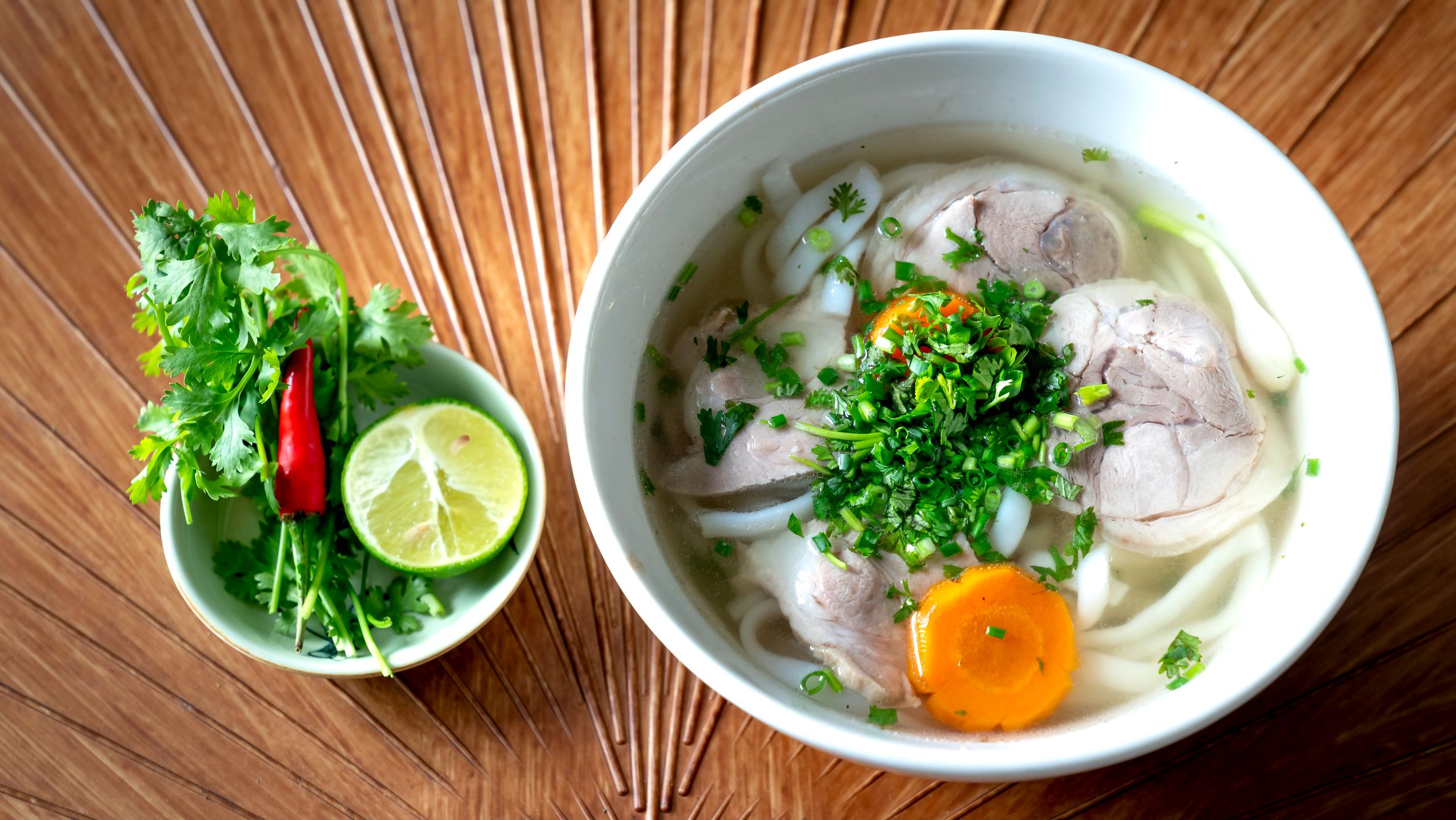 A vibrant bowl of Vietnamese Pho with fresh herbs and lime for a perfect meal.