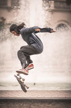 Energetic skateboarder performing a mid-air trick in front of a fountain.. energetic, skateboarder, performing