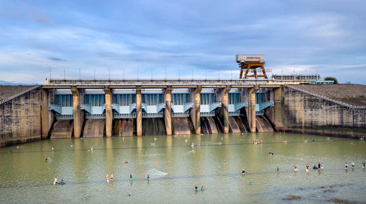 People Playing In Water Near Dam