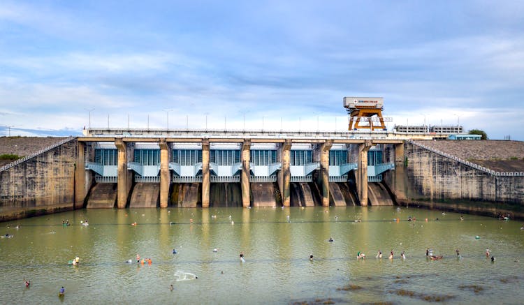 People Playing In Water Near Dam