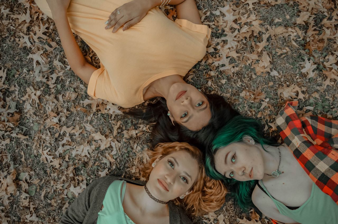 a top view of three women lying on a leafy ground capturing the essenc