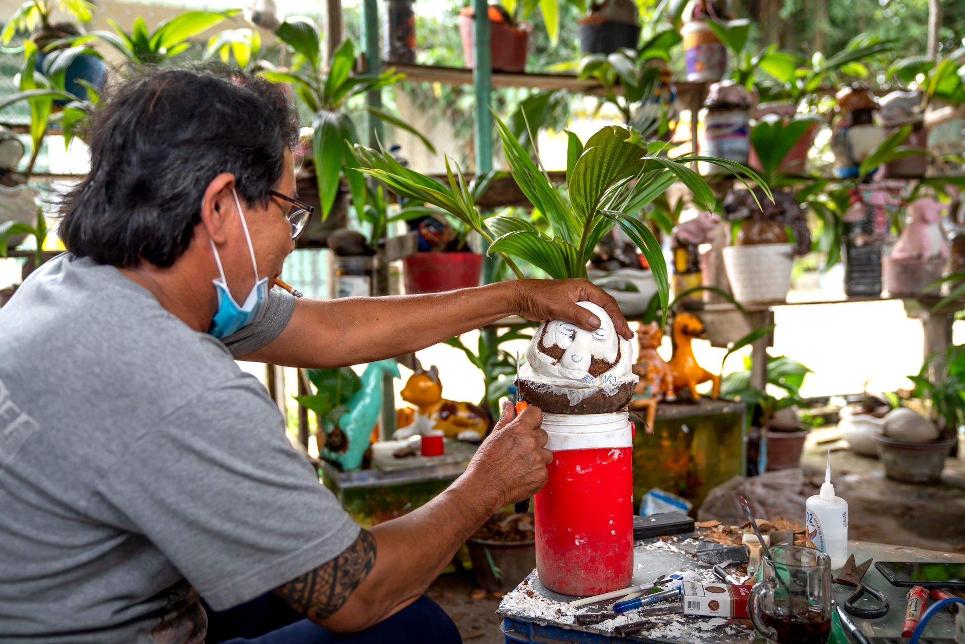 Man working with handmade pots and plants in a vibrant garden workshop setting.