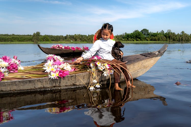 A Girls Sitting On A Boat With A Dog