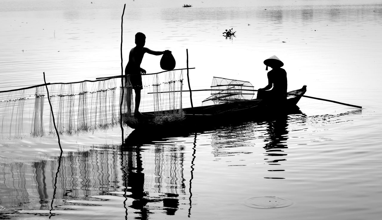 a black and white silhouette of fishermen working with nets on a tranq