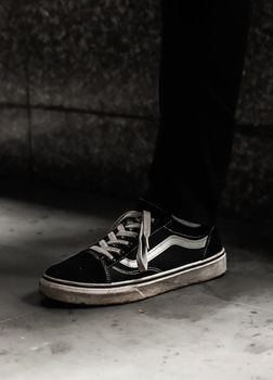 A stylish black sneaker on a concrete floor in a monochrome setting.